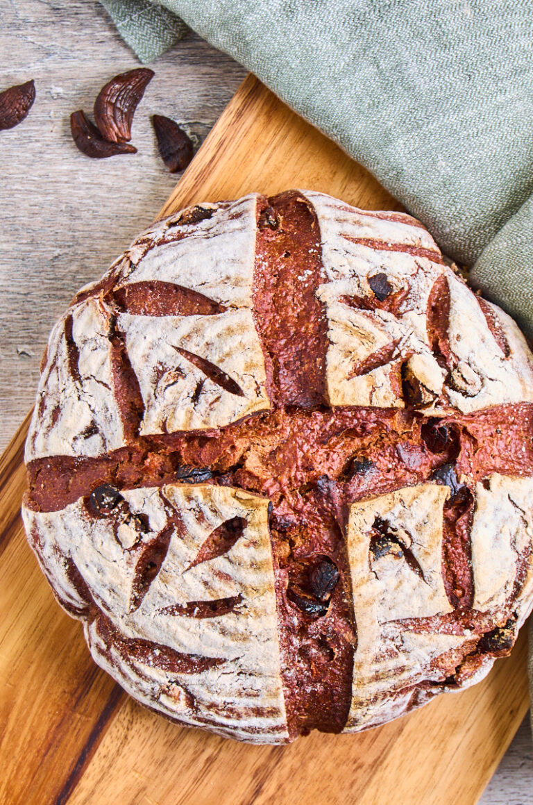 Black Garlic Sourdough Bread with Chocolate on a wooden board, a few black garlic cloves on the side. View from the top.