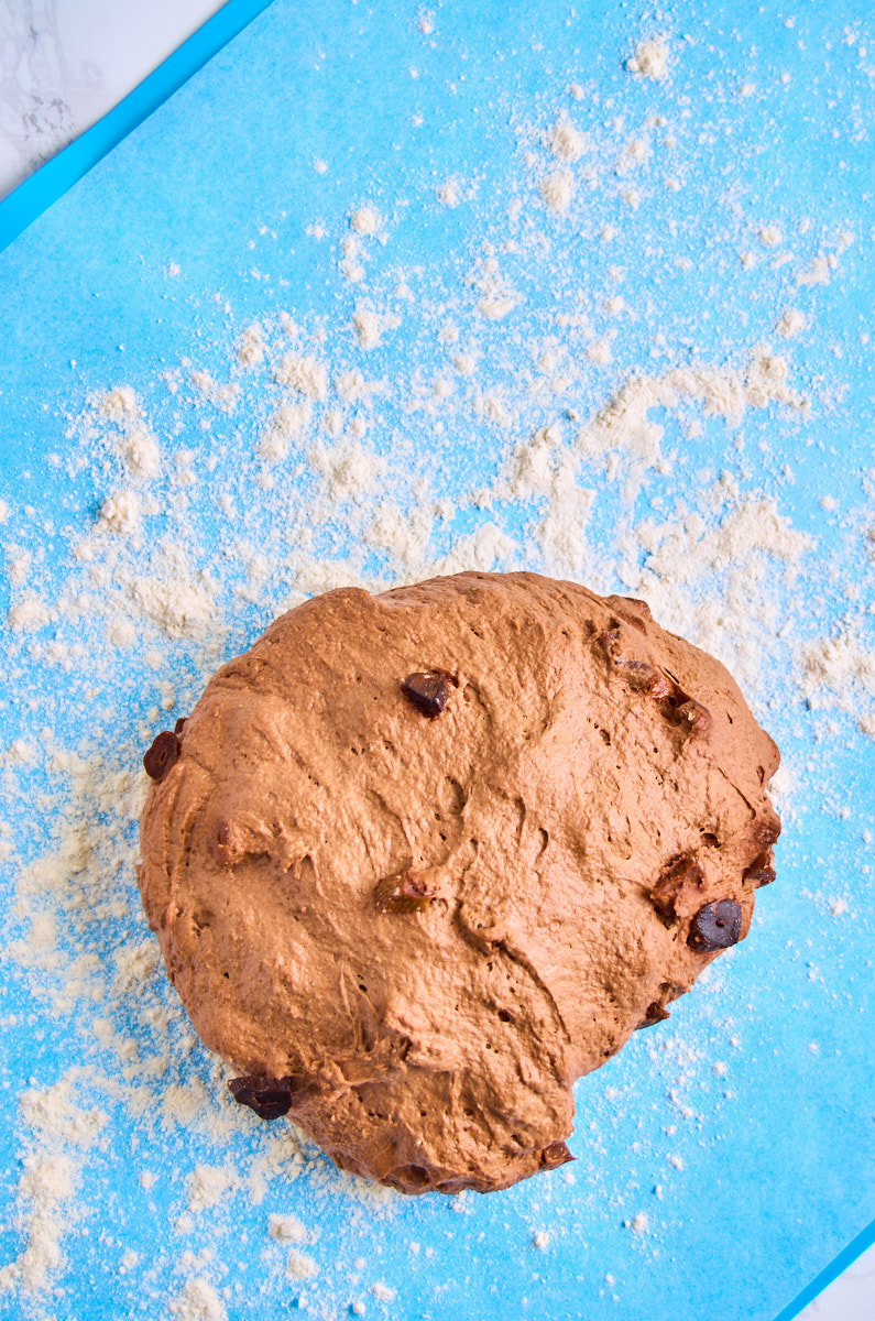 Black Garlic Sourdough Bread with Chocolate dough on a floured silicone mat for shaping.