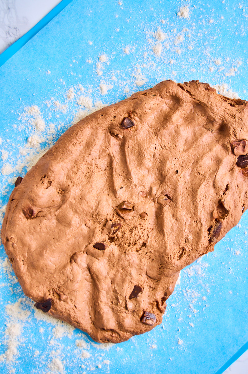 Black Garlic Sourdough Bread with Chocolate dough on a floured silicone mat, patted out into a long oval.