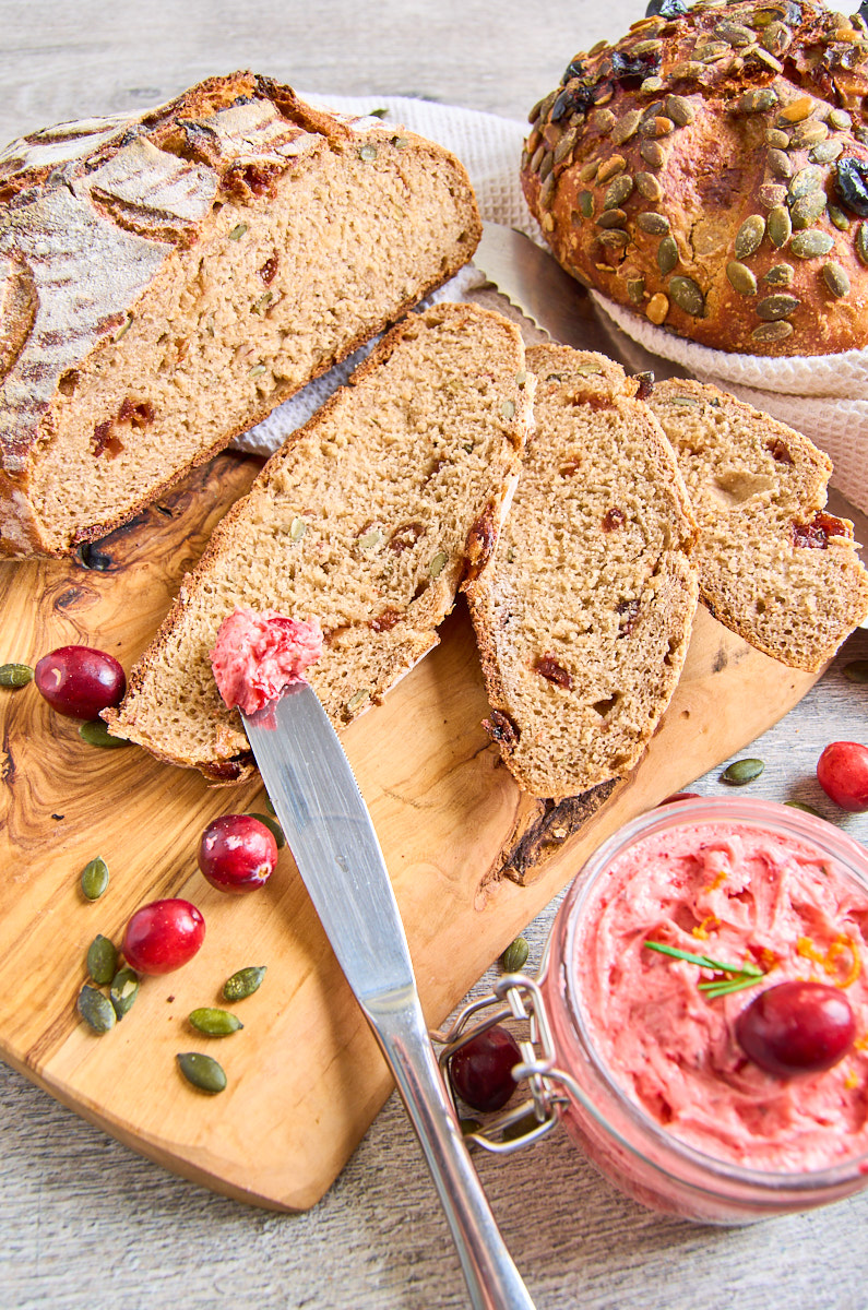 Cranberry Buckwheat Sourdough Bread with Rosemary and Pumpkin Seeds_ baked, 3 slices lying n front, showing the cranberry studded bread. Whipped cranberry butter beside the bread.